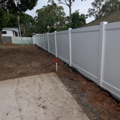 Long run of new white PVC fencing along a cleared side yard