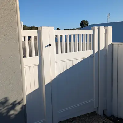 White PVC side gate with slatted top panel beside a house