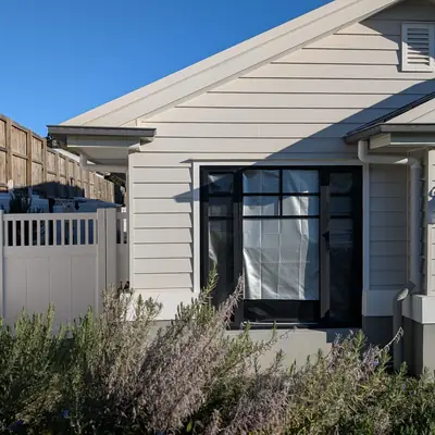 White PVC fence with slatted top section in front of a weatherboard home