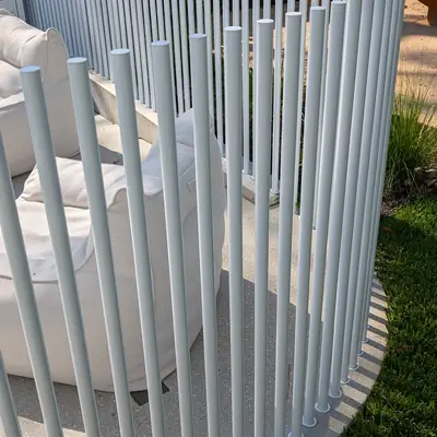 Curved white slat pool fence on a lawn
