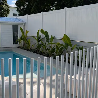White picket pool fence and PVC privacy fence around a backyard pool