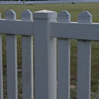 Close-up of white PVC picket fence posts with post caps
