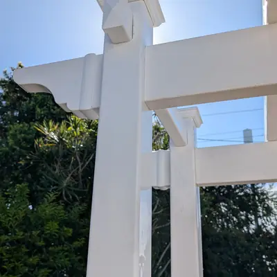 White PVC garden arbour posts and beams against a blue sky