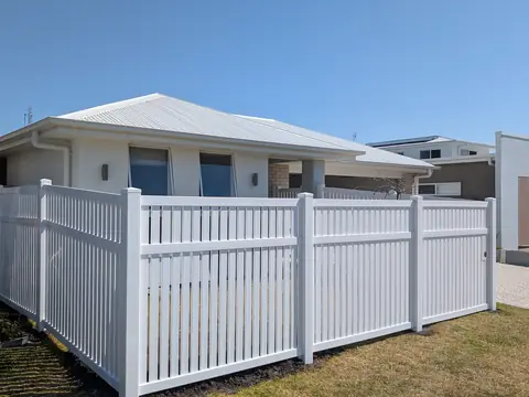 White PVC semi-privacy fence with spaced vertical slats in front of a house