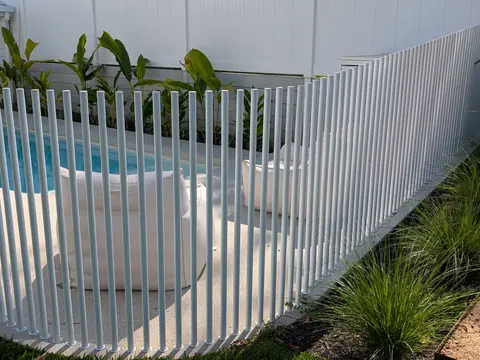 Curved white slat pool fence beside a pool